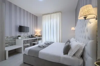 a white bedroom with a bed and a desk at Vatican Nausicaa in Rome