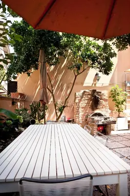a white picnic table with an umbrella and a fireplace at Casale 2.0 in Rome