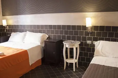 a bedroom with two beds and a stool and a table at Hotel Agorà in Rome