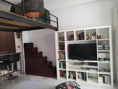 a living room with a tv in a white book shelf at Your secret place in Rome in Rome