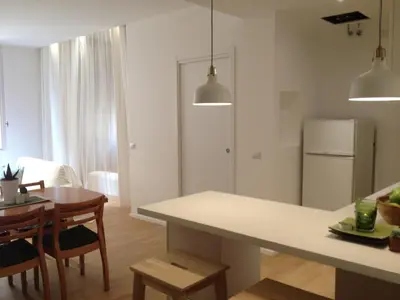 a kitchen and dining room with a table and a refrigerator at White Apartment in San Giovanni in Rome