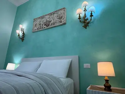 a bedroom with a blue wall with a bed and lights at Amedeo Apartment in Rome