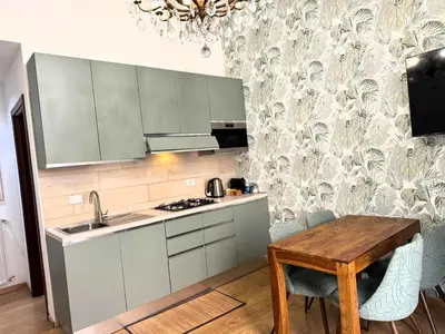 a kitchen with white cabinets and a wooden table at Amedeo Apartment in Rome
