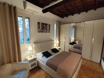 a bedroom with a bed and a chair and two windows at Cozy Navona Apartment in Rome