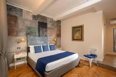 a bedroom with a large bed and a blue chair at Spagna Secret Rooms in Rome