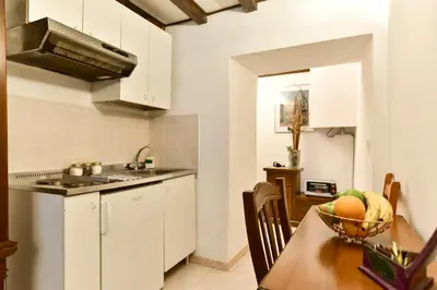 a kitchen with white cabinets and a table with a bowl of fruit at Loft Pantheon in Rome