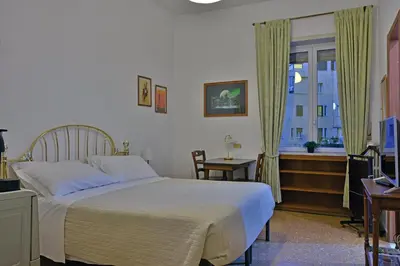 a bedroom with a bed and a desk and a window at Elion in Rome