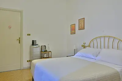 a bedroom with a white bed and a refrigerator at Elion in Rome