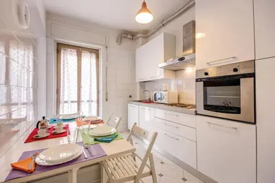 a kitchen with white cabinets and a table and chairs at VATICAN Gregory Apartment in Rome
