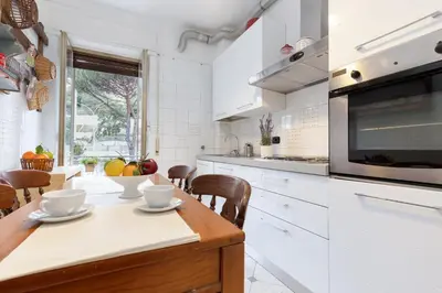 a kitchen with white cabinets and a wooden table at VATICAN Gregory Apartment in Rome