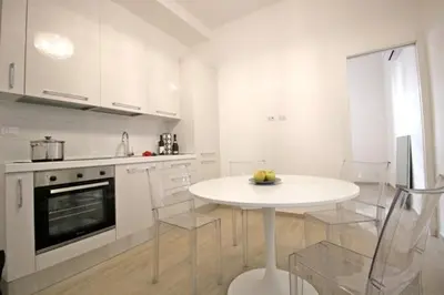 a white kitchen with a white table and chairs at Patrizi 2/a in Rome