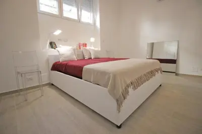 a white bedroom with a large bed with a red blanket at Patrizi 2/a in Rome