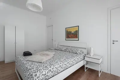 a white bedroom with a bed and a night stand at Claudio Vaticano appartamento in Rome