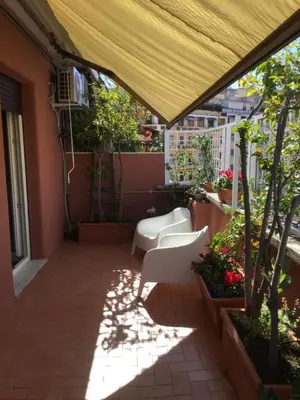 a patio with a yellow canopy and white chairs at Attico Pavia vicino Policlinico in Rome
