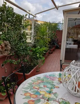 a patio with a table and some potted plants at Attico Pavia vicino Policlinico in Rome