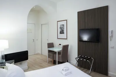 a room with a bed and a table and a television at Aureliana Luxury Apartments in Rome