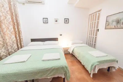 two beds in a white room with green blankets at Lemei House in Rome