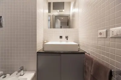 a bathroom with a white sink and a tub at Roman Forum Suite in Rome