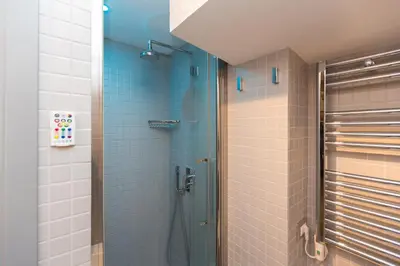 a bathroom with a shower with blue tiles at Roman Forum Suite in Rome