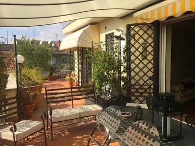 a patio with chairs and a table and an umbrella at Roma Suite Balduina in Rome