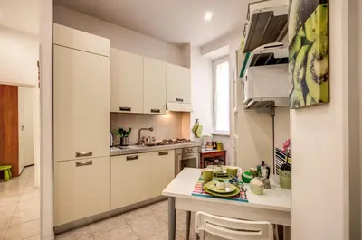 a small kitchen with white cabinets and a table at GreenSugarHome in Rome