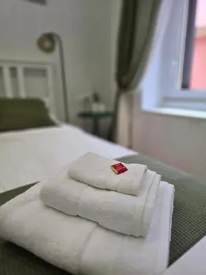 a bedroom with a white bed with towels on it at Rome Candia Holiday House in Rome