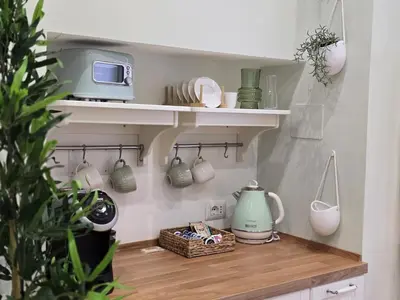 a kitchen with a shelf with cups and a microwave at Rome Candia Holiday House in Rome