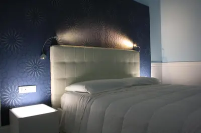 a bedroom with a white bed with a blue wall at Tuttelestrade - The apartment in Rome