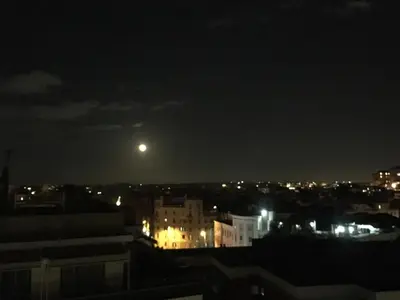 a moon in the sky over a city at night at Eufonia Vinyl Friendly Apartment in Rome