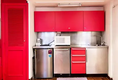 a kitchen with red cabinets and a microwave at RSH Balestrari Apartments in Rome