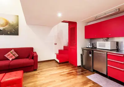 a living room with a red couch and a kitchen at RSH Balestrari Apartments in Rome
