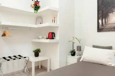 a white bedroom with a bed and white shelves at Maison Piazza Cavour in Rome