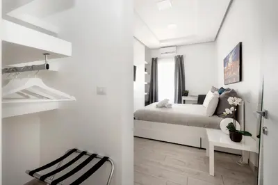 a white bedroom with a bed and a chair at Maison Piazza Cavour in Rome