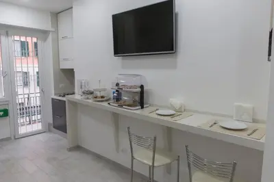 a kitchen with a counter with two chairs and a tv on the wall at Metronia Guest House in Rome
