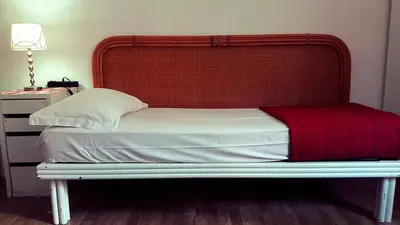 a bed with a wooden headboard and a red blanket at Roman Place in Rome