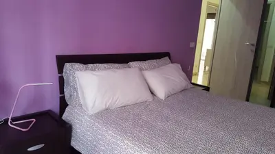 a purple bedroom with a bed with a white pillow at C'è posto per te in Rome