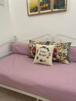 a bed with purple sheets and pillows with a bless myself pillow at Casa Vacanze Marzia in Rome