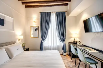 a hotel room with a bed and a desk with chairs at Babuino Palace&Suites in Rome