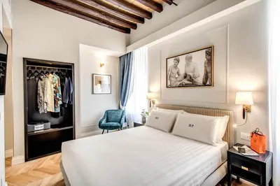 a bedroom with a white bed and a blue chair at Babuino Palace&Suites in Rome