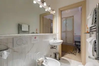 a white bathroom with a sink and a mirror at Rome Charming Suites in Rome