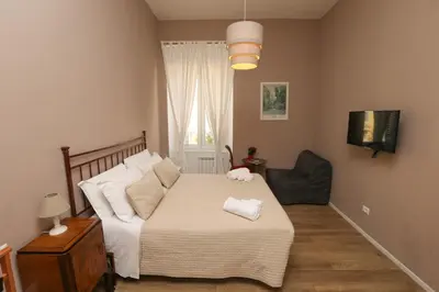 a bedroom with a bed and a chair and a television at Vatican Garden Rooms in Rome