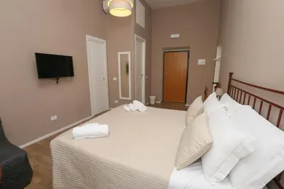 a bedroom with a bed with white pillows and a television at Vatican Garden Rooms in Rome