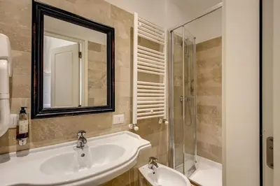 a white room with a bed and a flat screen tv at Hotel Tito in Rome
