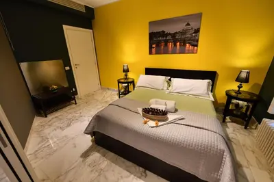 a bedroom with a large bed and yellow walls at The Roman Residence in Rome