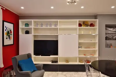 a living room with a large white entertainment center with a television at The Roman Residence in Rome