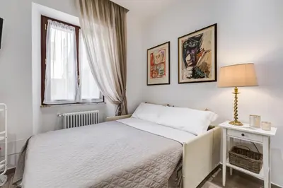 a white bedroom with a bed and a lamp at AS Vaticano Apartment in Rome