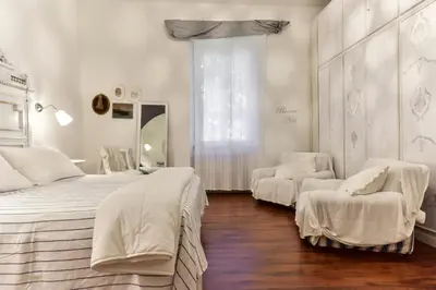 a white bedroom with two beds and a window at Maru Apartment in Rome