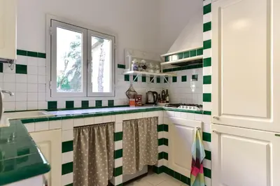 a kitchen with green and white tiles on the wall at Maru Apartment in Rome