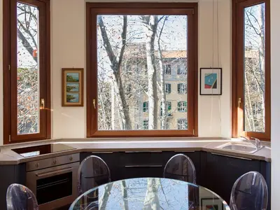 a kitchen with a glass table and two windows at The Apartments - Vatican in Rome