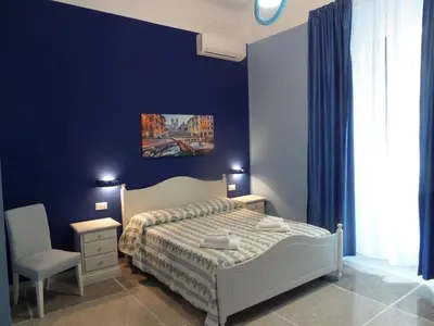 a bedroom with a bed and a blue wall at 325 Rooms ai Fori in Rome